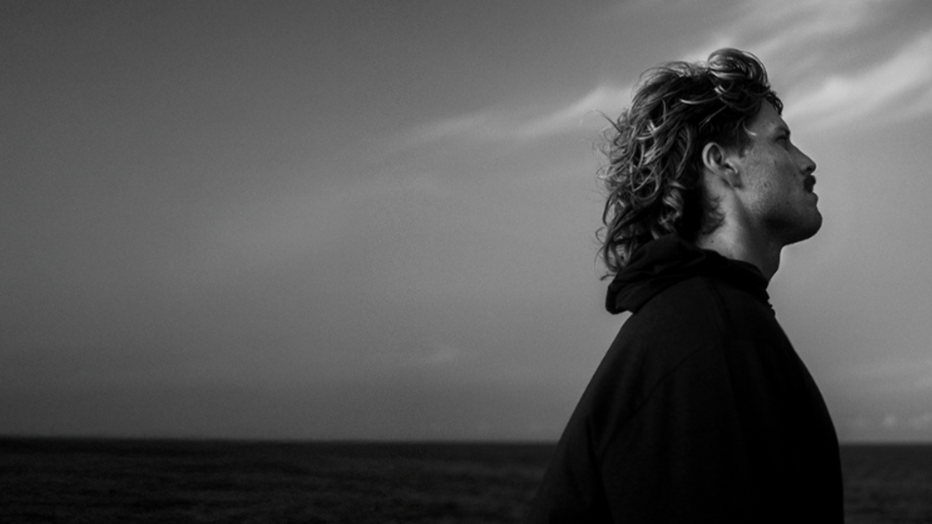 Singer Ziggy Alberts posing against an ocean backdrop.