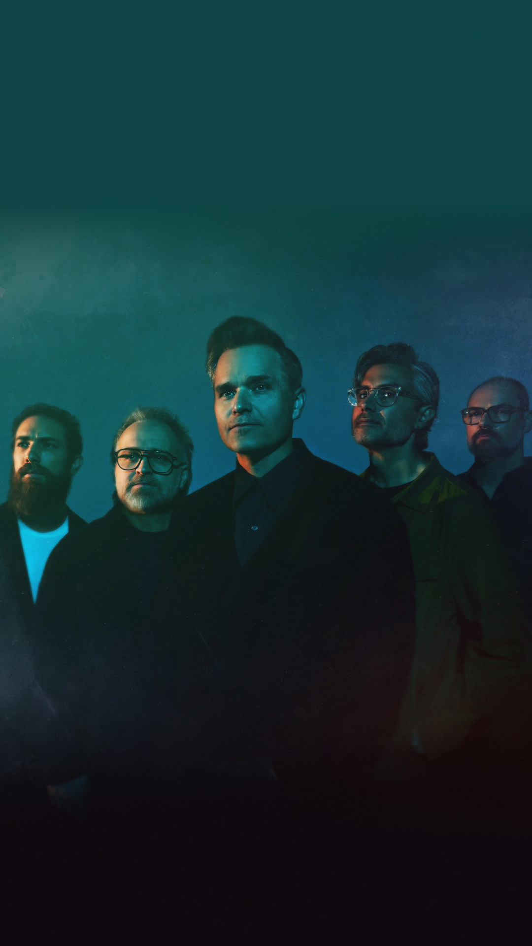Death Cab For Cutie band members dressed in black and posing against a blue background.