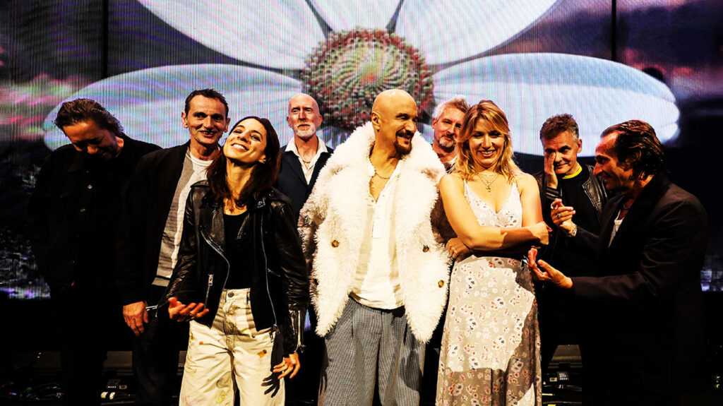 James band members dressed in various costumes and standing on stage together.