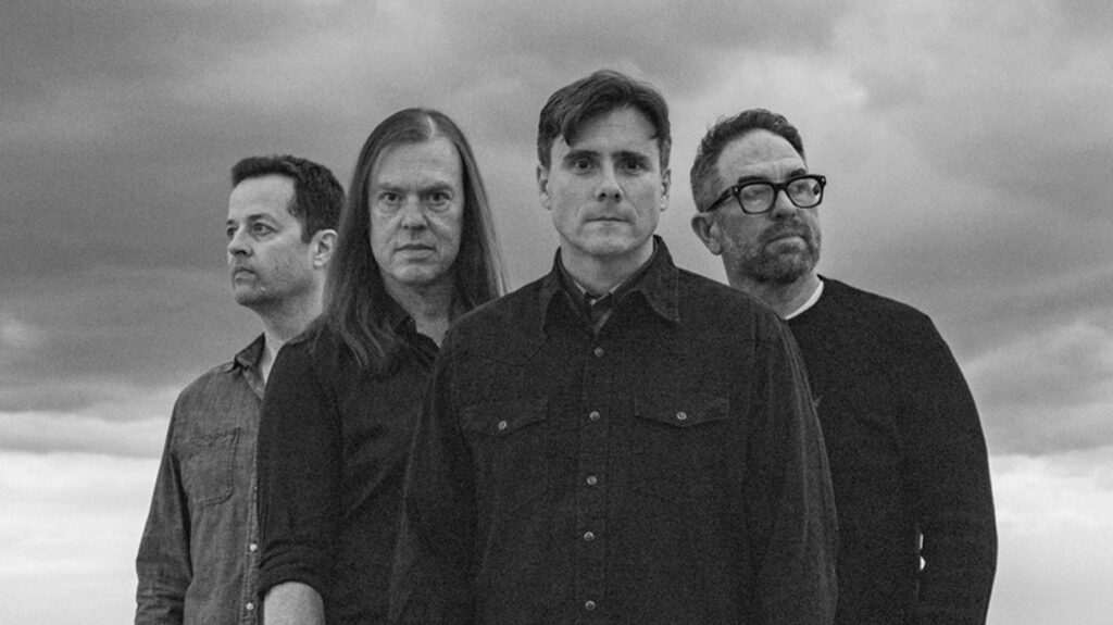 Four male band members of Jimmy Eat World pose together in a black and white photo.